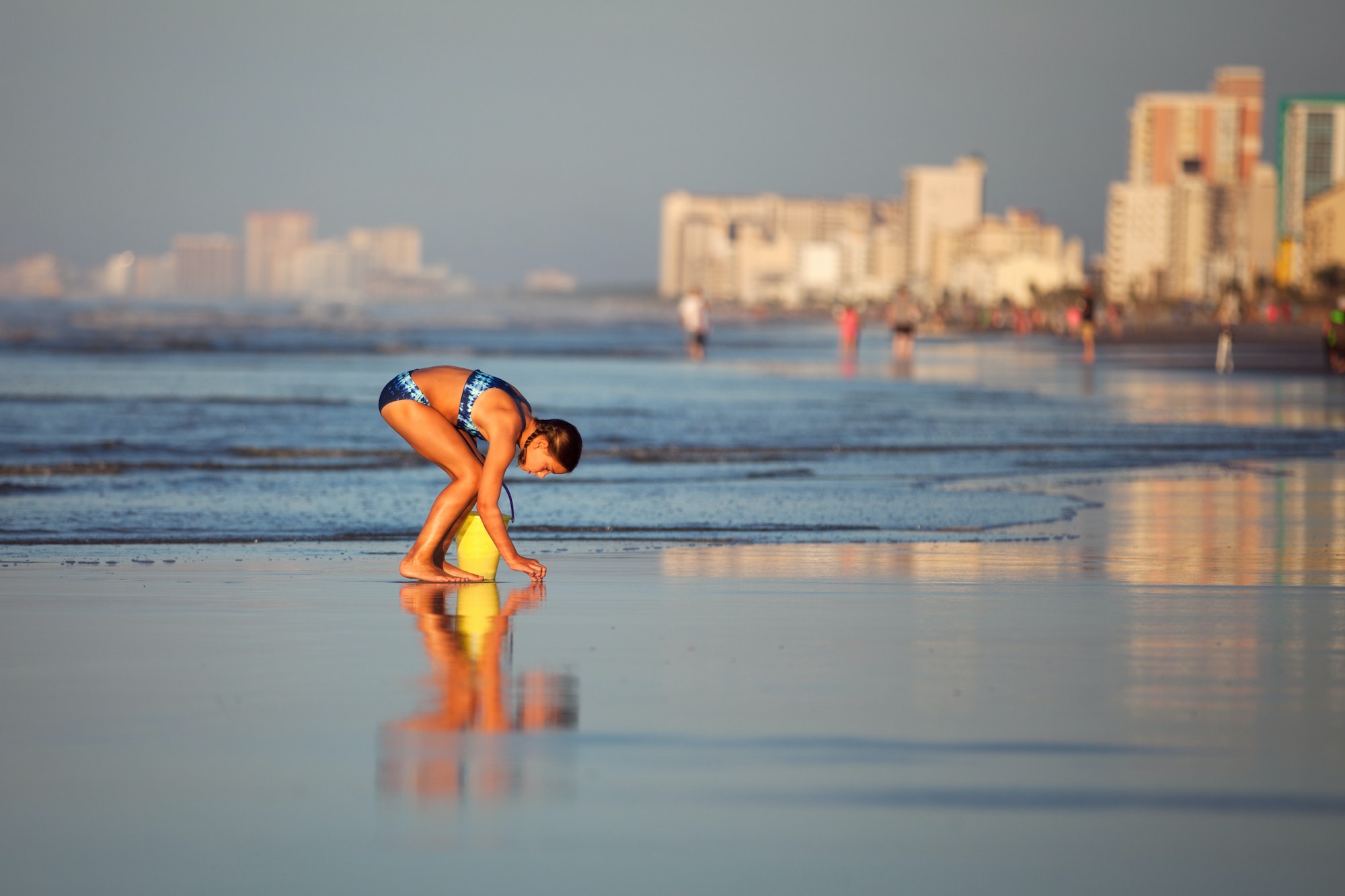 Girl on beach picking up seashells, North Myrtle Beach, South Carolina, United States, North America