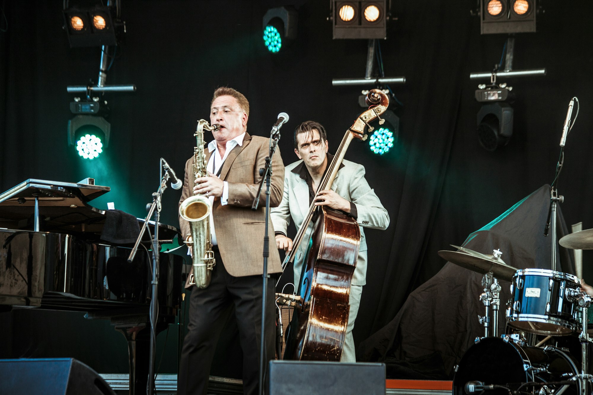 The bass player and the saxophonist of a jazz band perform during a concert.