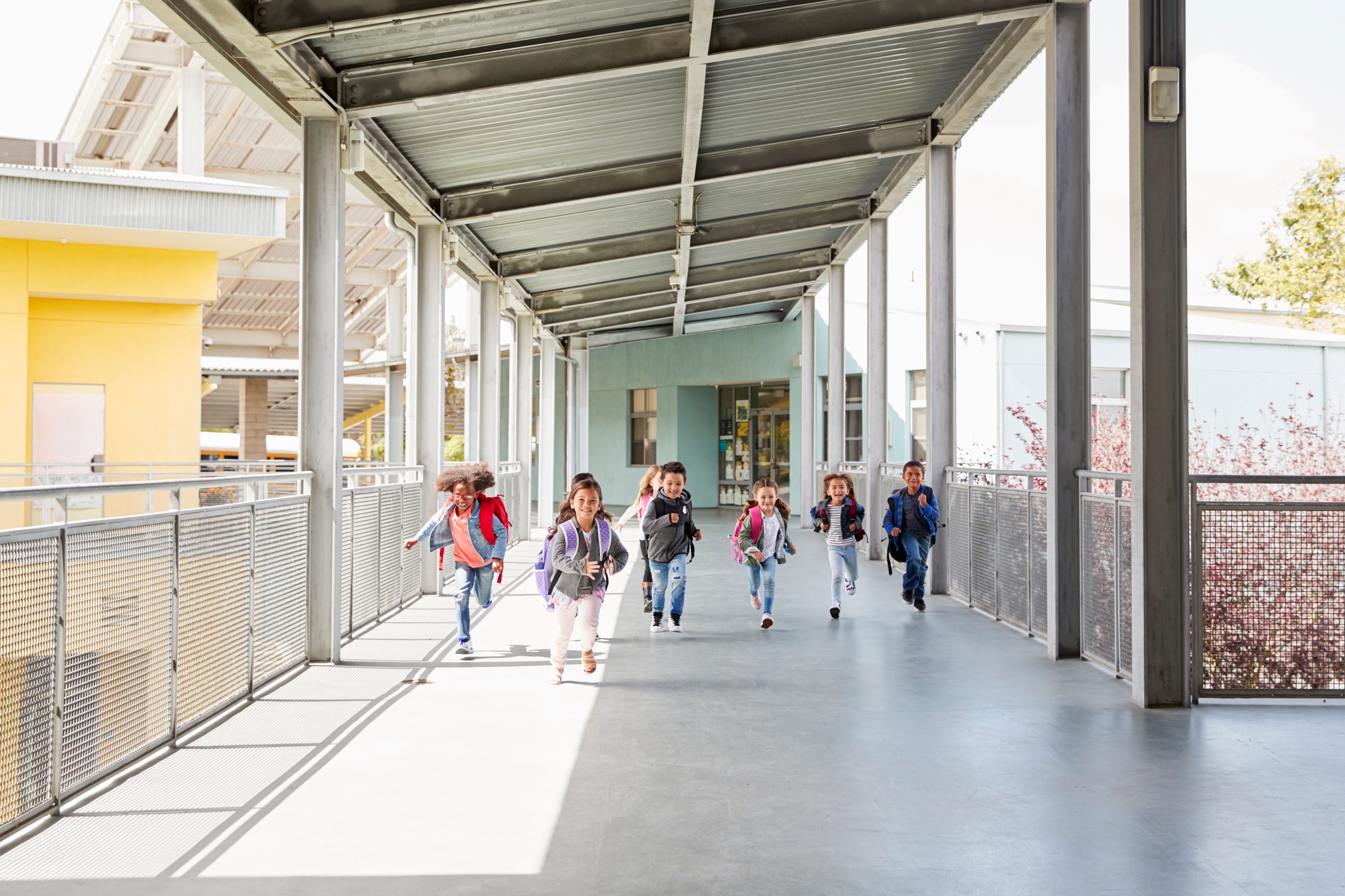 Young school kids running on a walkway in their school